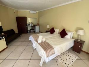 - une chambre avec un grand lit blanc et des oreillers rouges dans l'établissement Pofadder Hotel by Country Hotels, à Pofadder