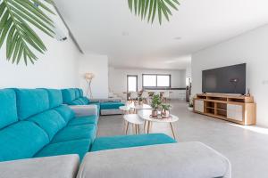 a living room with a blue couch and a tv at Villa Locki in Lourinhã