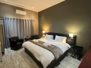 - une chambre avec un grand lit et une chaise dans l'établissement Pofadder Hotel by Country Hotels, à Pofadder