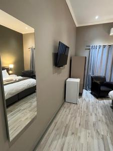 Cette chambre comprend un lit, une télévision et un miroir. dans l'établissement Pofadder Hotel by Country Hotels, à Pofadder