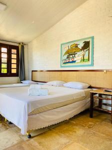 Pousada Villa Kite Flecheiras في ترايري: سرير كبير في غرفة مع صورة على الحائط