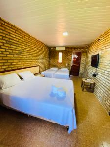 a room with four beds and a brick wall at Pousada Villa Kite Flecheiras in Trairi