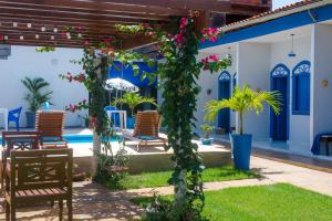 a pergola with flowers and chairs in a yard at Pousada Vila de Charme in Barreirinhas