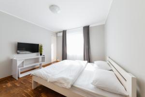 a white bedroom with a bed and a tv at Luxury Apartments “Bozdosh” in Uzhhorod