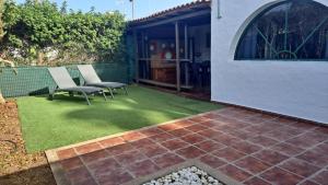 einen Hof mit zwei Stühlen und eine Terrasse mit Gras in der Unterkunft Bungalow en el sur de Gran Canaria in Las Palmas de Gran Canaria