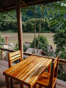 a wooden table and chairs on a porch with a view of a river at Meexok river view in Nongkhiaw