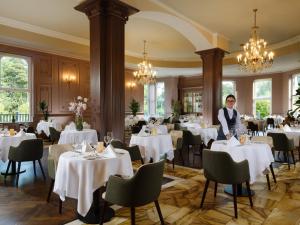 a woman standing in a dining room with tables at Killashee Hotel in Naas