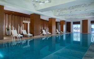 a swimming pool in a hotel lobby with white chairs at Park Chalet, Shahdag, Autograph Collection in Shahdag