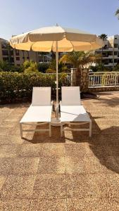 two white chairs and an umbrella on a patio at Luxuriöse Duplex Ferienwohnung in sehr ruhiger Wohnanlage mit Meerblick in Palm-mar