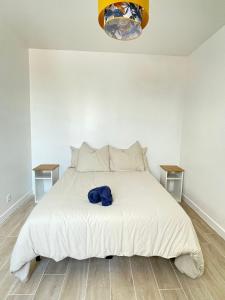 ein Schlafzimmer mit einem weißen Bett und einem blauen Hemd darauf in der Unterkunft Chez Jérôme et Dina in Aubervilliers