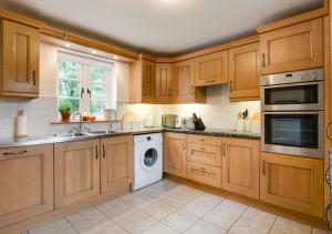 una cucina con armadi in legno e lavastoviglie bianca di Wood Lodge a Monks Eleigh