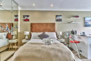 a bedroom with a large bed and a red chair at Hyde Park on the Square in Cape Town