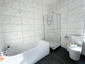 a white bathroom with a tub and a toilet at South Pier Apartments by Sasco in Blackpool