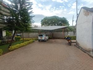 un furgone bianco parcheggiato in un vialetto con un baldacchino di Amigo apartments a Kisumu