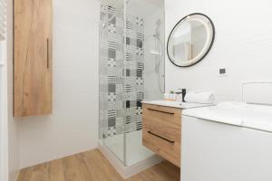 a bathroom with a shower and a sink and a mirror at Praga Apartment Łukowska by Renters in Warsaw