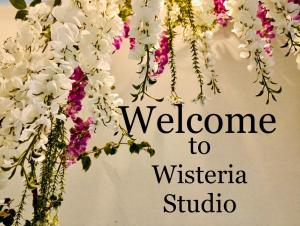 un cartello che dice benvenuto allo studio Wisteria con dei fiori di Wisteria a Nafpaktos