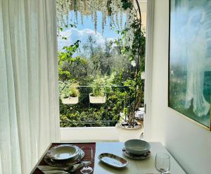 un tavolo con piatti e bicchieri di fronte a una finestra di Wisteria a Nafpaktos