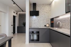a kitchen with gray cabinets and a sink and a stove at Luxury Apartments “Bozdosh” in Uzhhorod