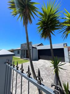 two palm trees and a fence in front of a house at Family Holiday Home Rental in Port Elizabeth in Lorraine