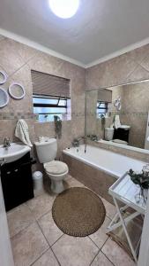 Family Holiday Home Rental in Port Elizabeth في Lorraine: حمام مع حوض ومرحاض ومغسلة