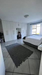 Family Holiday Home Rental in Port Elizabeth في Lorraine: غرفة نوم مع سرير وسجادة على الأرض