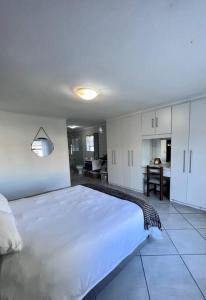 a bedroom with a large white bed and a kitchen at Family Holiday Home Rental in Port Elizabeth in Lorraine