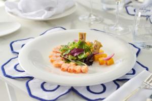 a plate of food with shrimp and vegetables on a table at Hotel Scalinatella in Capri