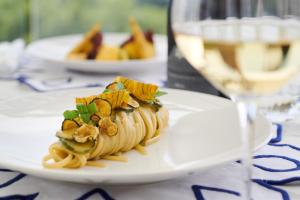 a white plate with pasta and a glass of wine at Hotel Scalinatella in Capri