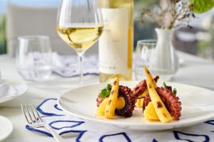 a white plate with food and a glass of wine at Hotel Scalinatella in Capri