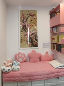 Una cama rosa con animales de peluche encima. en 星享民宿 Instar Homestay Jazz Suites 4 Kuching, en Kuching