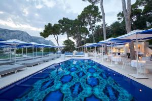 a pool with chairs and tables and umbrellas at Hotel Scalinatella in Capri