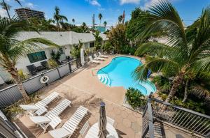 einen Blick über einen Pool mit Stühlen und Palmen in der Unterkunft The Roth Hotel, Treasure Island, Florida in St Pete Beach