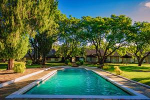 a swimming pool in a yard with trees at Great Zimbabwe Hotel in Nyanda