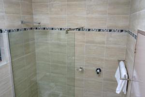 a shower with a glass door in a bathroom at Great Zimbabwe Hotel in Nyanda +32 photos