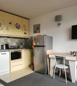 a small kitchen with a refrigerator and a table at terrasses du Morel in La Lechere