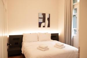 Un dormitorio con una cama blanca con toallas. en Taskou Luxury Suites en Tesalónica