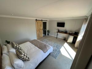 a bedroom with a white bed and a television at The Guesthouse Kokstad in Kokstad