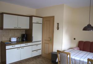 a kitchen with white cabinets and a table and a bed at Fremdenzimmer Klinge in Haina