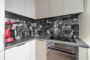 a kitchen with black and white tiles on the wall at Margi Smart Apartament HANZA POOL SAUNA in Szczecin