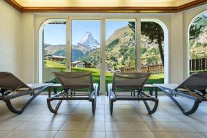 Zimmer mit Stühlen und einem Tisch mit Bergblick in der Unterkunft Hotel Alpenroyal in Zermatt