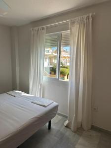 1 dormitorio con 1 cama y una ventana con cortinas blancas en Seaside House, bellísima casa en Marbella en Marbella