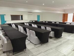 a conference room with black tables and white chairs at Adante Lodge & Conferencing in Mthatha