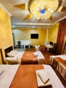 a hotel room with three beds and a television at Lux Palace Hotel in Kutaisi