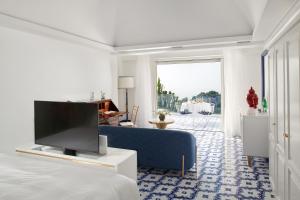 a living room with a blue couch and a tv at Hotel Scalinatella in Capri