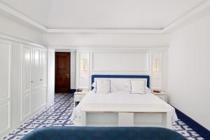 a bedroom with a white bed and a blue couch at Hotel Scalinatella in Capri