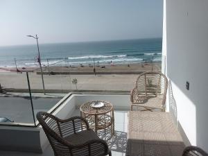 a balcony with a table and chairs and the beach at Hawaii piscine-pool in Kenitra