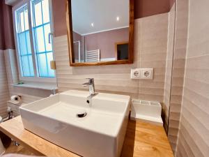 La salle de bains est pourvue d'un lavabo blanc et d'un miroir. dans l'établissement CASA REHSE I Stilvolles Apartment I 24h-Self-Check-in I kostenlos Parken & WLAN I 55-Zoll-Smart&Kabel-TV I ÖPNV, à Erfurt