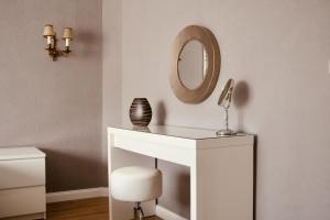 a white dressing table with a mirror and a stool at CASA REHSE I Stilvolles Apartment I 24h-Self-Check-in I kostenlos Parken & WLAN I 55-Zoll-Smart&Kabel-TV I ÖPNV in Erfurt