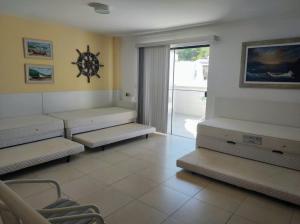 sala de estar con bancos y reloj en la pared en Praia Grande- Villa da Praia - Cobertura Duplex!, en Arraial do Cabo