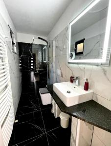 une salle de bain en noir et blanc avec un lavabo et un miroir dans l'établissement Villa Nikolla, à Lovran